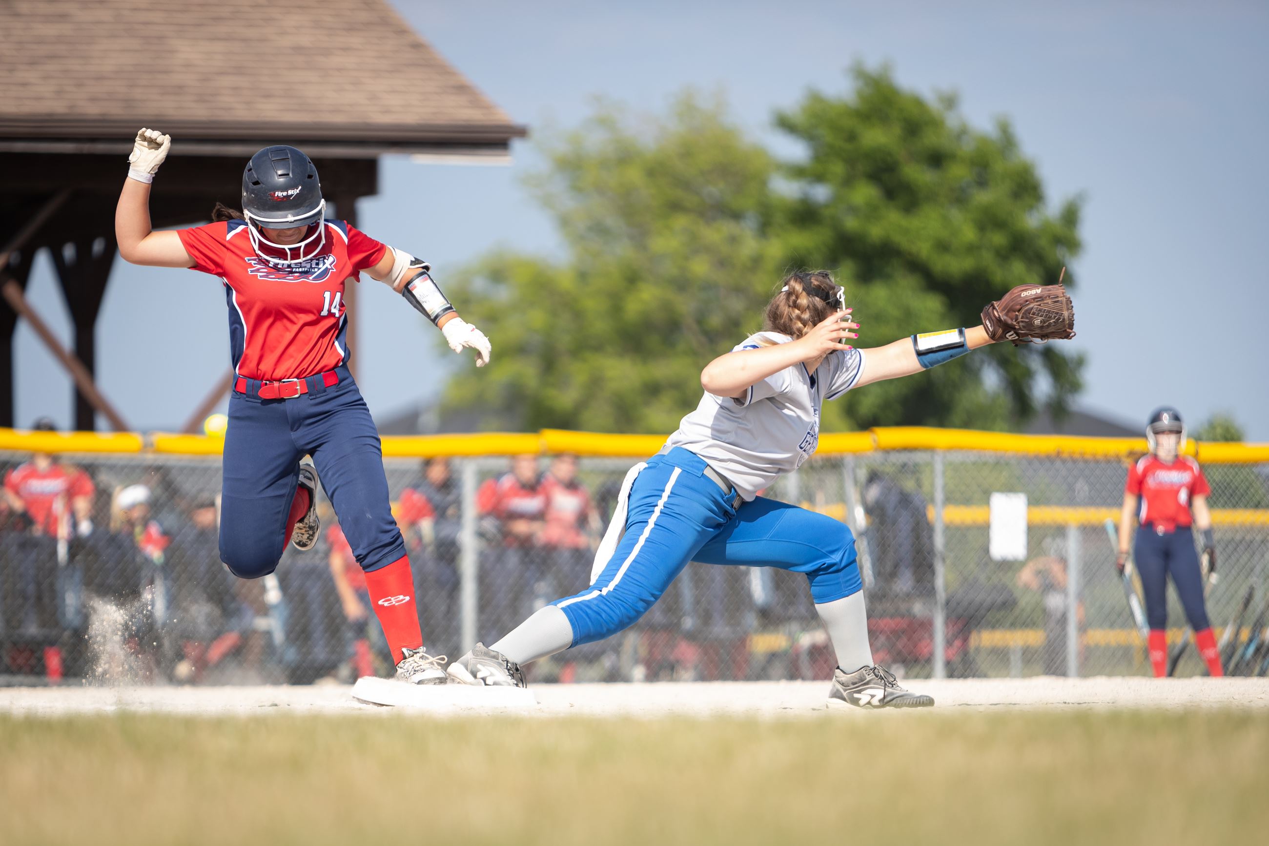 two softball players on opposite teams on base